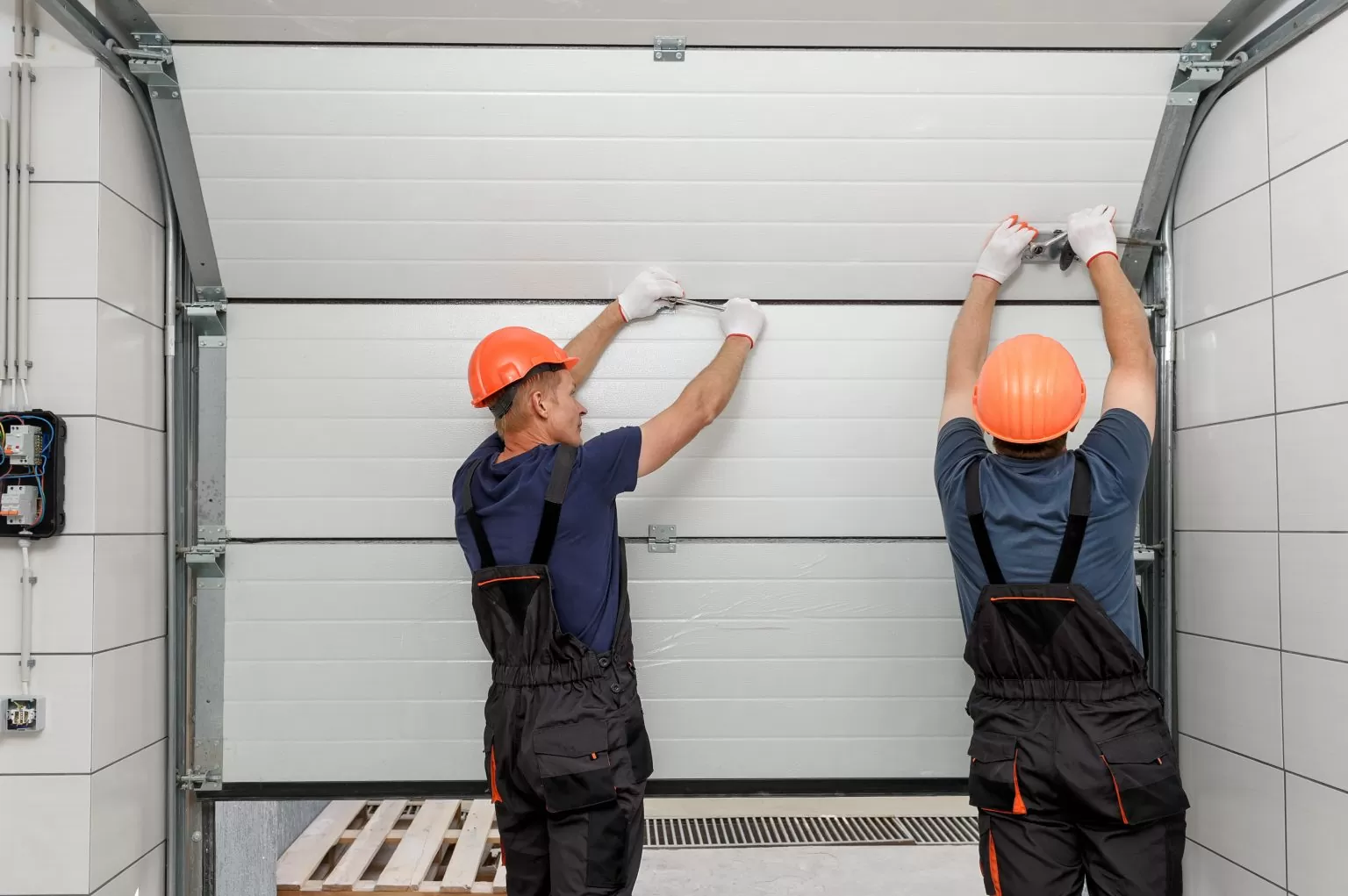 Two men workers repairing a garage door