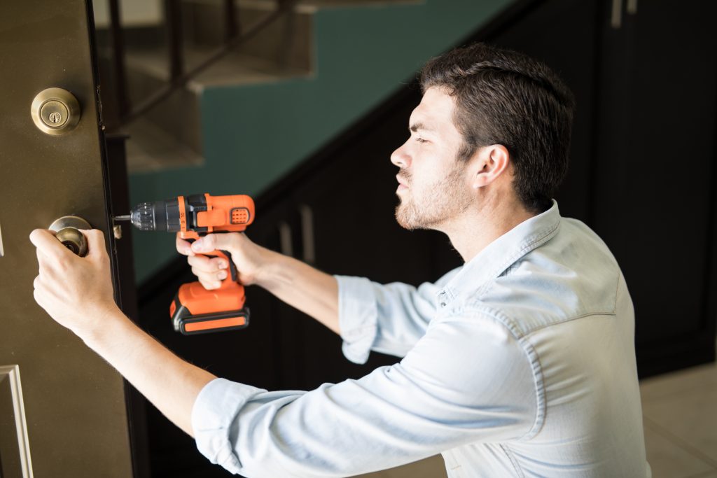 A man repairing a door with an electric drill